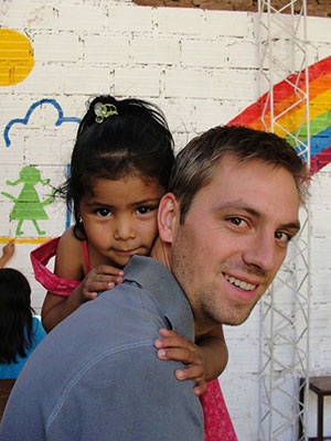 Tyler Regehr gets a hug from Carlita who lives with her parents in a prison in Bolivia. Tyler and his wife Renae are working with prison families in Bolivia, serving with MCC. Photo: MCC BC