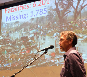 Board chair Len Bloch addresses MCC B.C.’s annual meeting, as slides of Philippines typhoon Haiyan play behind him. British Columbians contributed more than a half-million dollars for MCC relief efforts following that disaster. Photos: Sophie Tiessen-eigbike