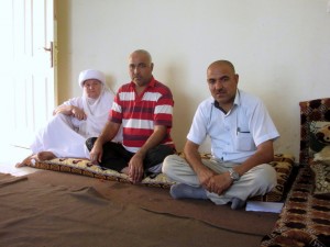 Qasim, right, with his brother Haji, centre, and mother Huda, left, sit in the living area of the new apartment they rent using assistance from a project with MCC's partner organization REACH and funded by a Canadian government grant. Qasim and 28 other relatives were displaced from their homes in Sinjar by an advance of the Islamic State group. They all lived together for 10 months in an unfinished building before receiving rent assistance from REACH and moving to the new apartments. (MCC photo/Kaitlin Heatwole)